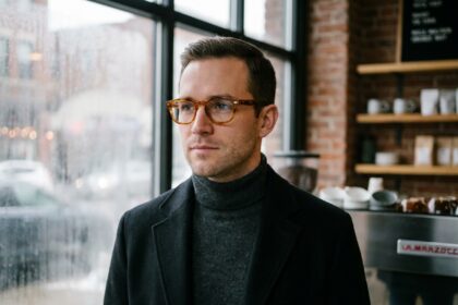 Homme élégant portant des lunettes en acétate écaille de tortue dans un café urbain en hiver, style masculin raffiné