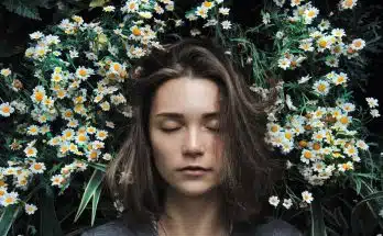 woman closing her eyes on white flower